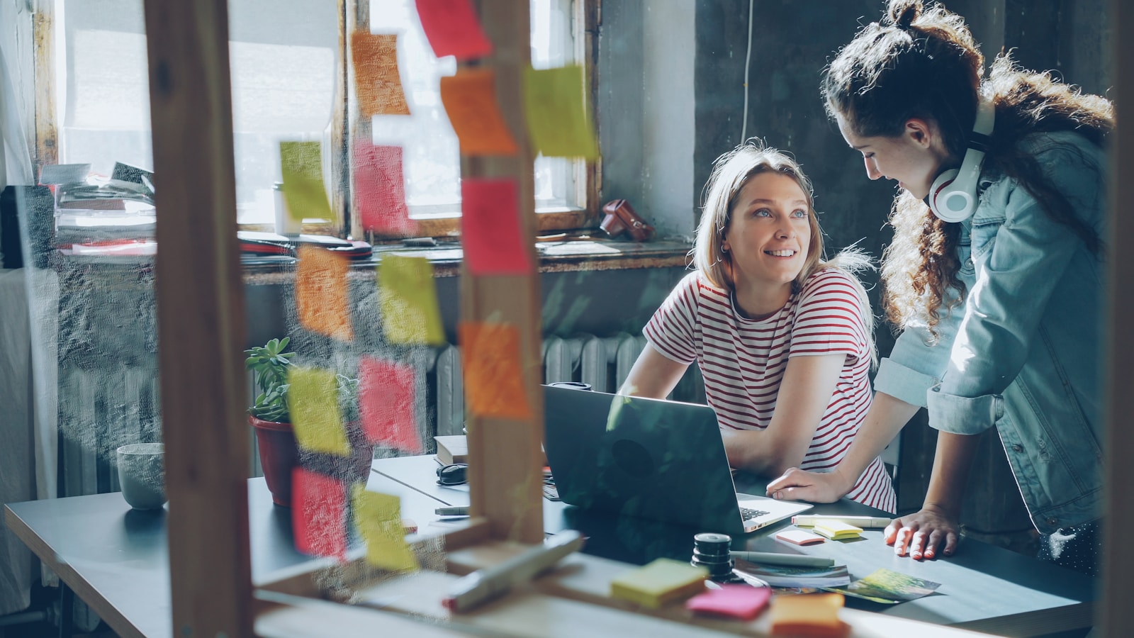 Business Are OKRs and Why They Matter for Business Success 1 Two women collaborate over a laptop in an office.
